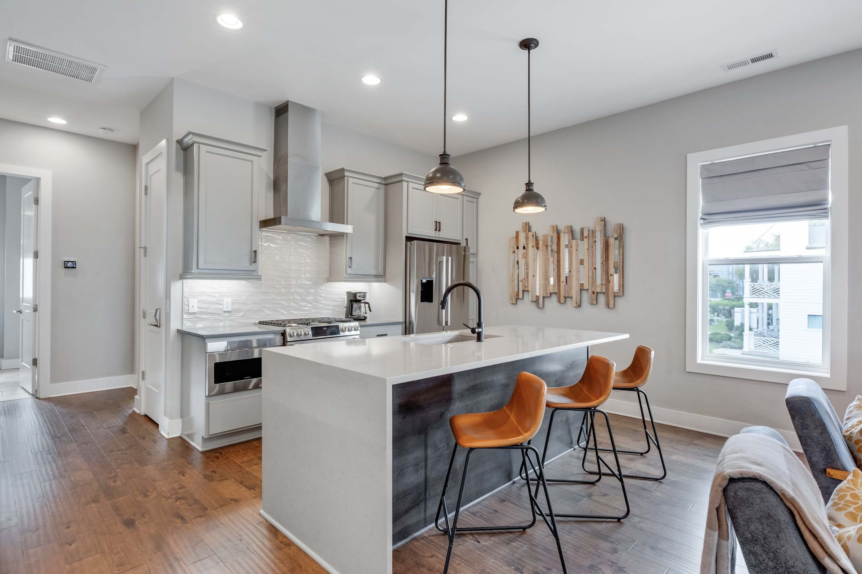 A modern kitchen with a central island, stainless steel appliances, and pendant lighting.