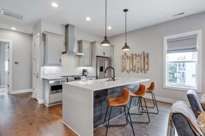 Una cocina moderna con una isla central, electrodomésticos de acero inoxidable e iluminación colgante.