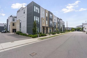 Un edificio residencial moderno de varios pisos con techo plano, ventanas amplias y una calle limpia y ordenada.