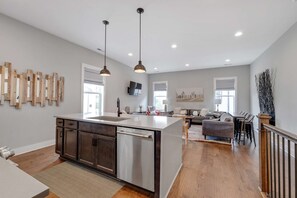 A spacious kitchen with a central island, pendant lighting, and a dining area with a sofa and chairs.