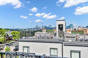 A rooftop with a view of a city skyline, including a 'Music City' sign, and a fenced area with outdoor seating. - 2 Massive Nashville Homes - Stunning Downtown View (Nashville)