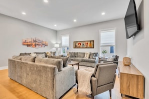 A modern living room with grey sofas, a wooden coffee table, and artwork on the walls.