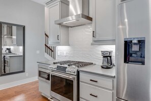 Una cocina moderna con electrodomésticos de acero inoxidable, armarios blancos y horno empotrado.