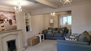 Ein Wohnzimmer mit Kamin, einer Couch, einem blauen Sessel und einer Chandelier.