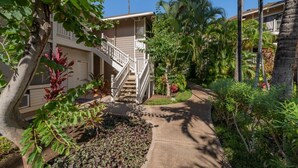 A residential building with a covered outdoor area, a staircase, and tropical vegetation. - Grand Champions Villas 61- Wailea (Kihei)