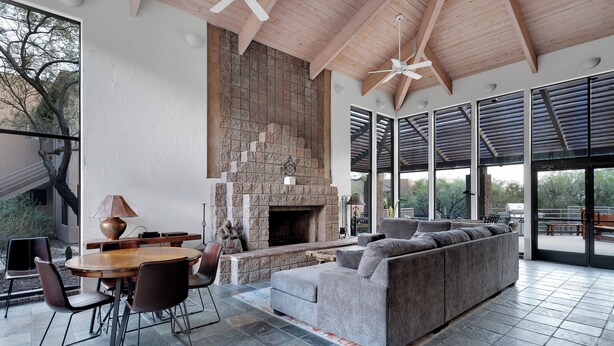A spacious living area with a stone fireplace, a large gray sofa, and a dining table with chairs.