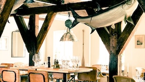Un comedor con mesa de madera, sillas y adornos de peces colgantes.