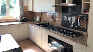 Una cucina con mobili bianchi, un fornello a gas e diversi utensili da cucina appesi al muro.