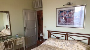 Una camera da letto con un letto, una scrivania, una sedia, una cassettiera, uno specchio e una porta.