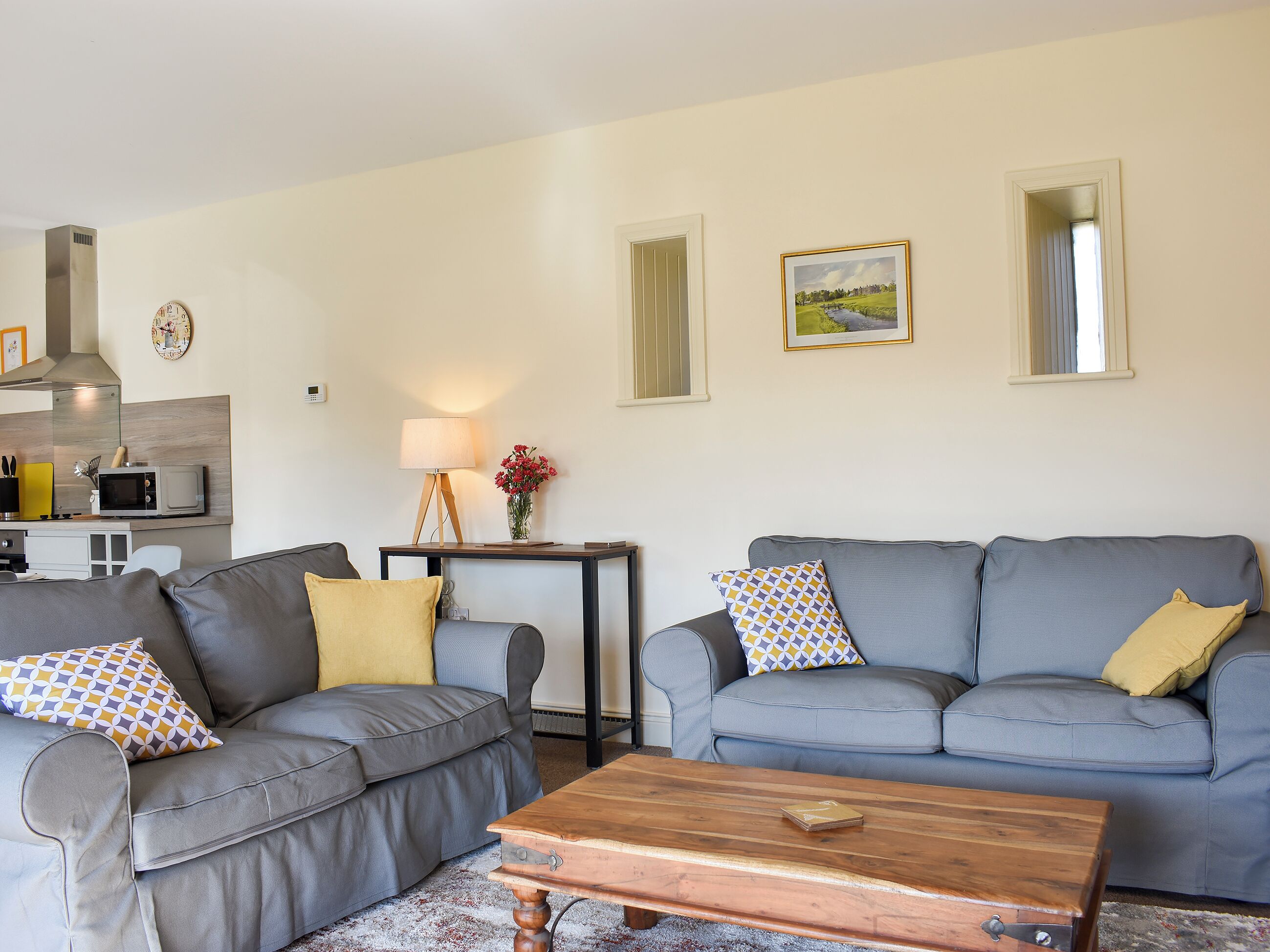 A living room with two grey sofas, a wooden coffee table, a lamp, and a painting on the wall.