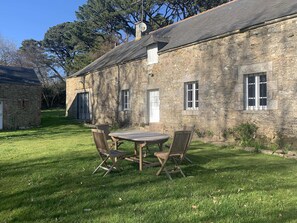 A stone building with a wooden table and chairs in the yard. - La Bergerie de la Seignerie de Trémohar, a charming spot just 15 minutes from the beach (Berric)
