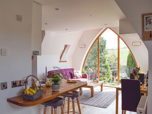 A loft-style room with a dining area, a large window, and a view of the outdoors.