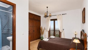A bedroom with a bed, a nightstand, a lamp, a window with curtains, and a view of the outside. - Villa Benizan Private Pool, Sea Views, A/C, WiFi (Torrox)