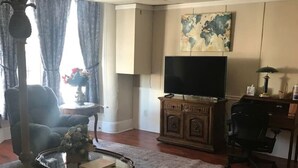 Un salon comprenant une télévision, une table basse, un canapé, une lampe et une carte du monde accrochée au mur.