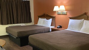 Une chambre d’hôtel avec deux lits, une table de chevet avec un téléphone et une lampe fixée au mur.