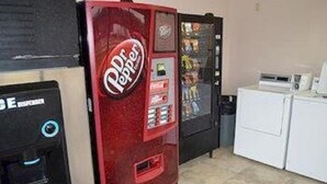 A Dr Pepper vending machine and a coffee machine in a room with a washing machine.