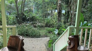 A wooden porch with two chairs and a cat. - HUGE! Belize Vacation Lodge, 1 to 6 Private Cottages Plus Fully Equipped Kitchen (Punta Gorda)