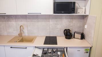 Cocina compacta con lavamanos, microondas, tostadora y un cajón con utensilios.