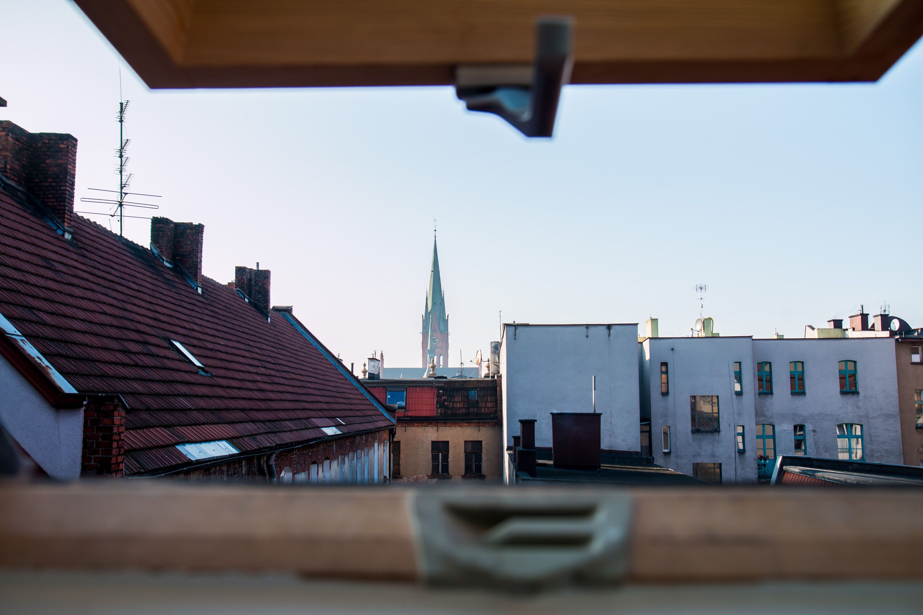 Une vue d’un bâtiment avec un toit rouge et une tour en arrière-plan.