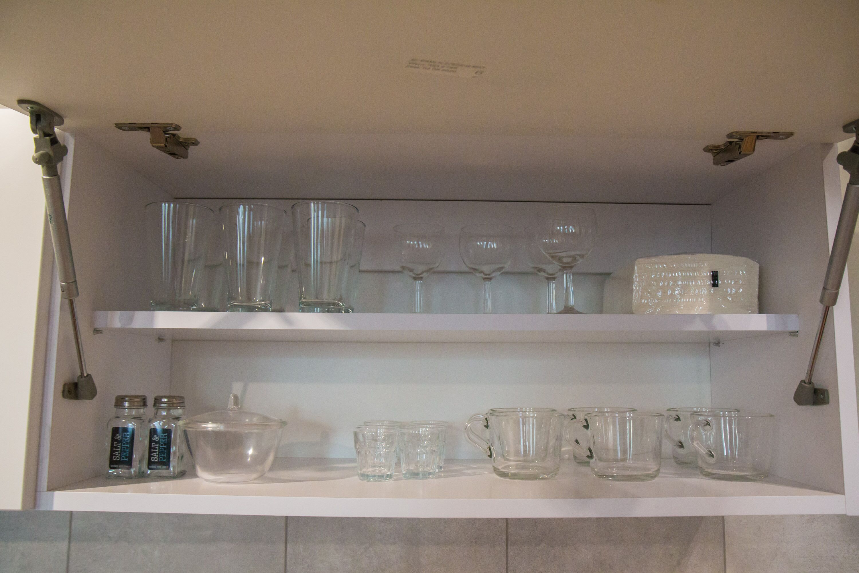 A kitchen shelf with various glassware and containers.