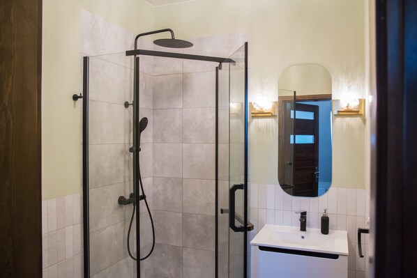 Une salle de bain avec une douche à parois de verre, un lavabo blanc et un miroir.