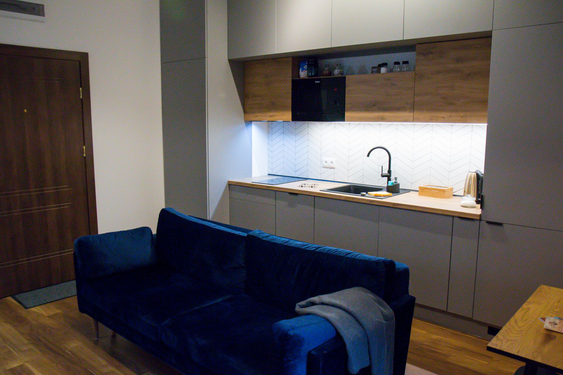 A compact kitchen with a built-in oven, a sink, and wooden cabinets.