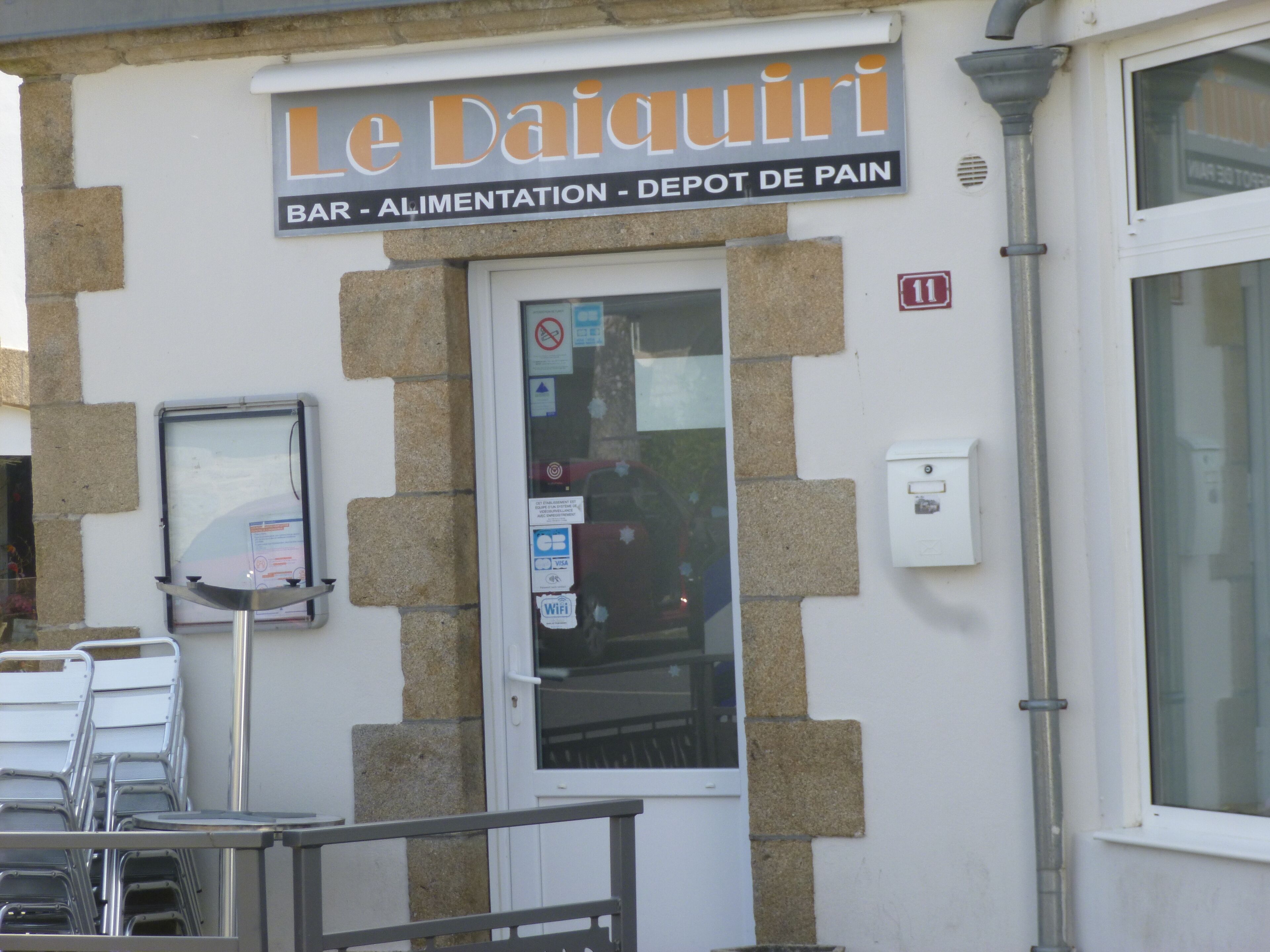 Une devanture de magasin avec une enseigne indiquant : « Le Daiquiri Bar – Épicerie – Point de vente de pain ».