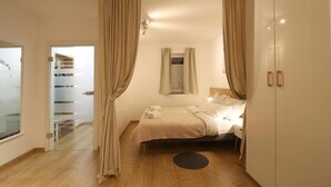 Une chambre à coucher comprenant un lit, une table de chevet, une commode, une fenêtre avec des rideaux et une armoire.
