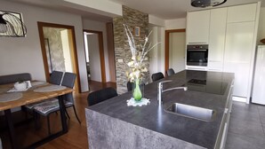 Une cuisine moderne dotée d’un îlot central, d’un four encastré et de meubles de rangement blancs.