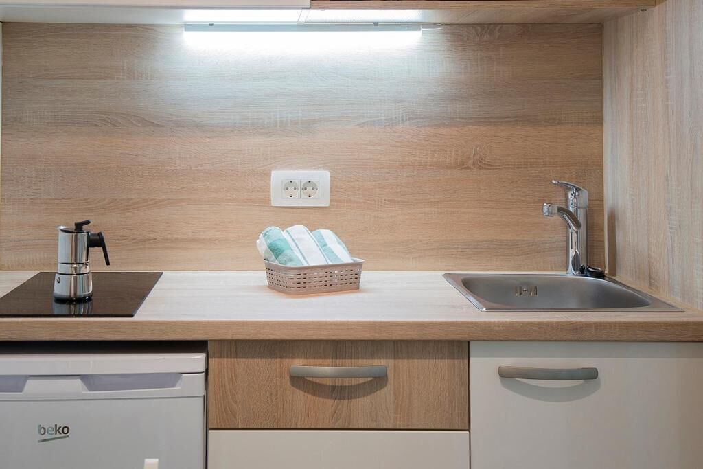 A modern kitchen with a built-in stove, a sink, and a basket of towels.