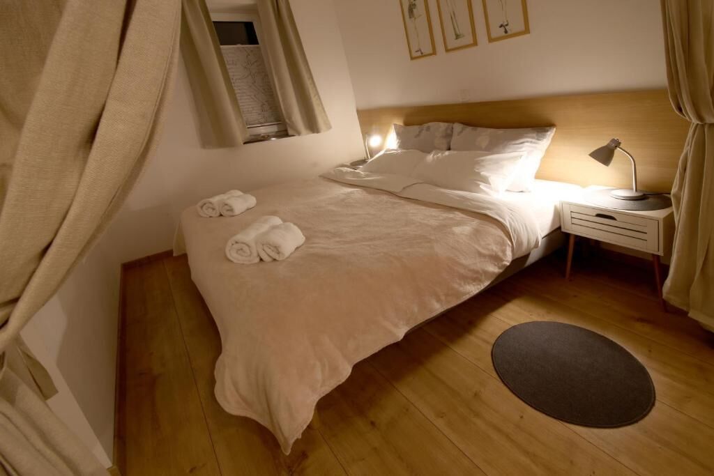 Un letto rifatto con cura, con testiera, lampada da comodino e un piccolo tavolino.