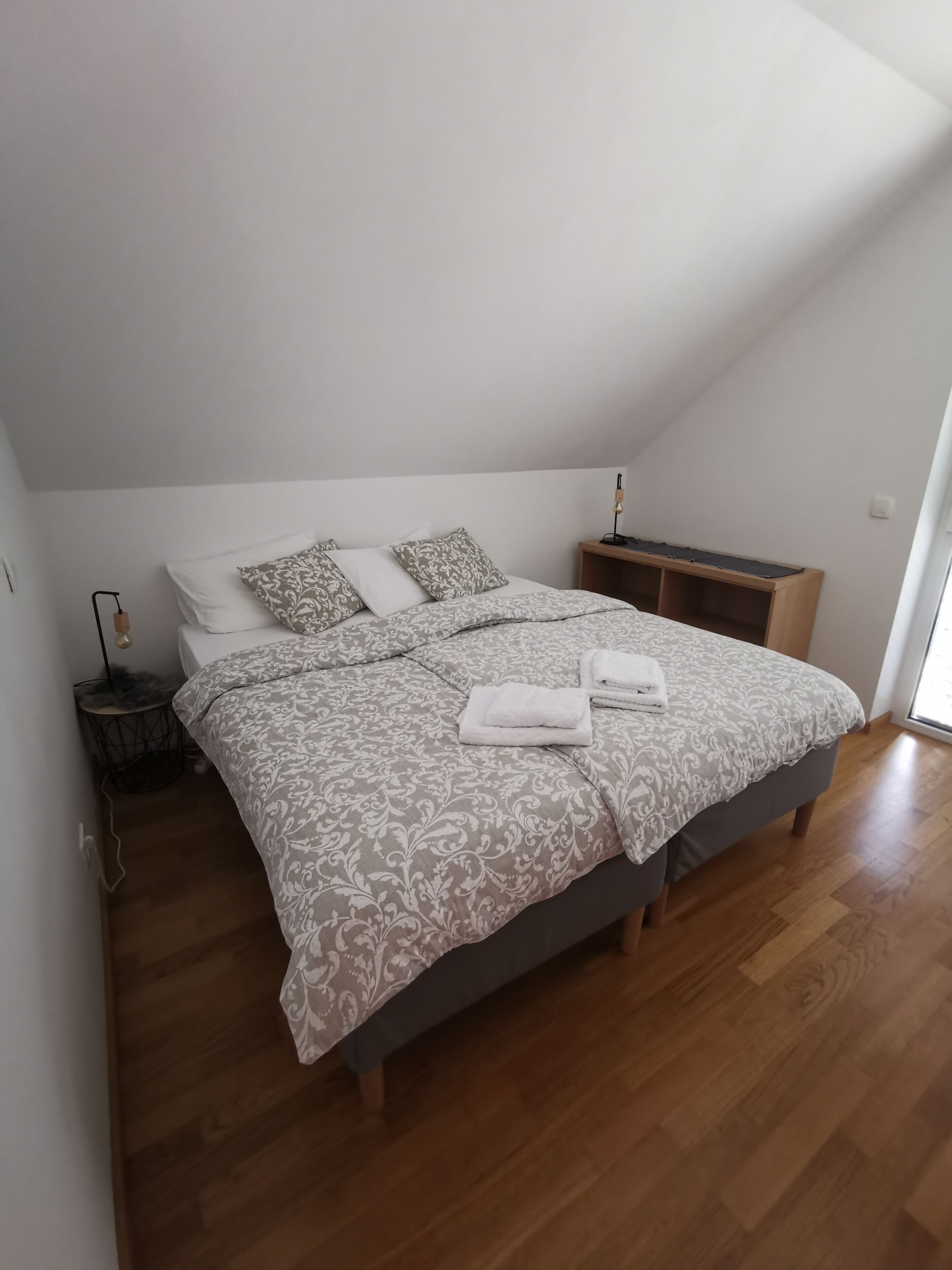 Une chambre à coucher avec un lit, des oreillers, une table de chevet et une lampe.