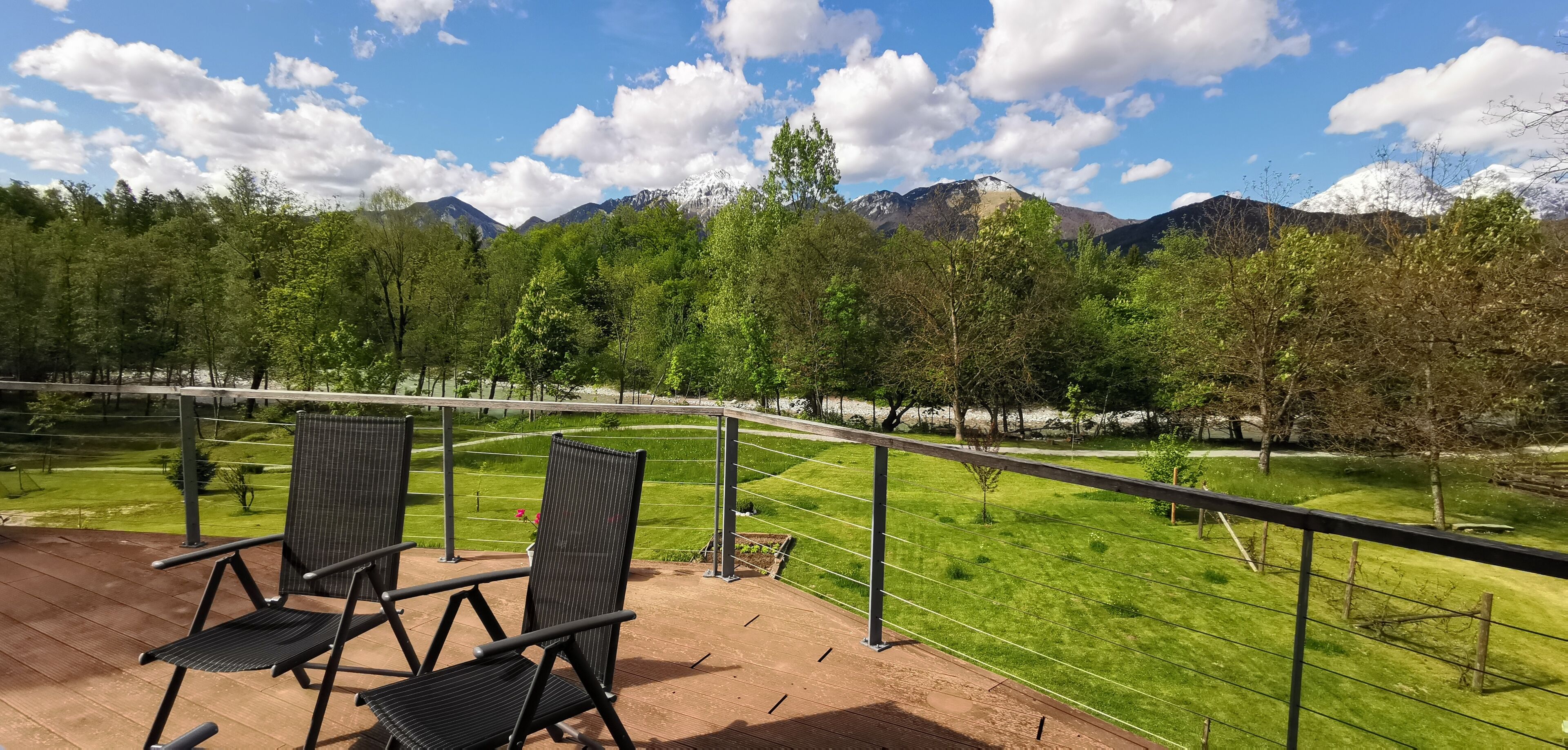 A terrace with two chairs overlooking a landscaped garden and a mountain view.