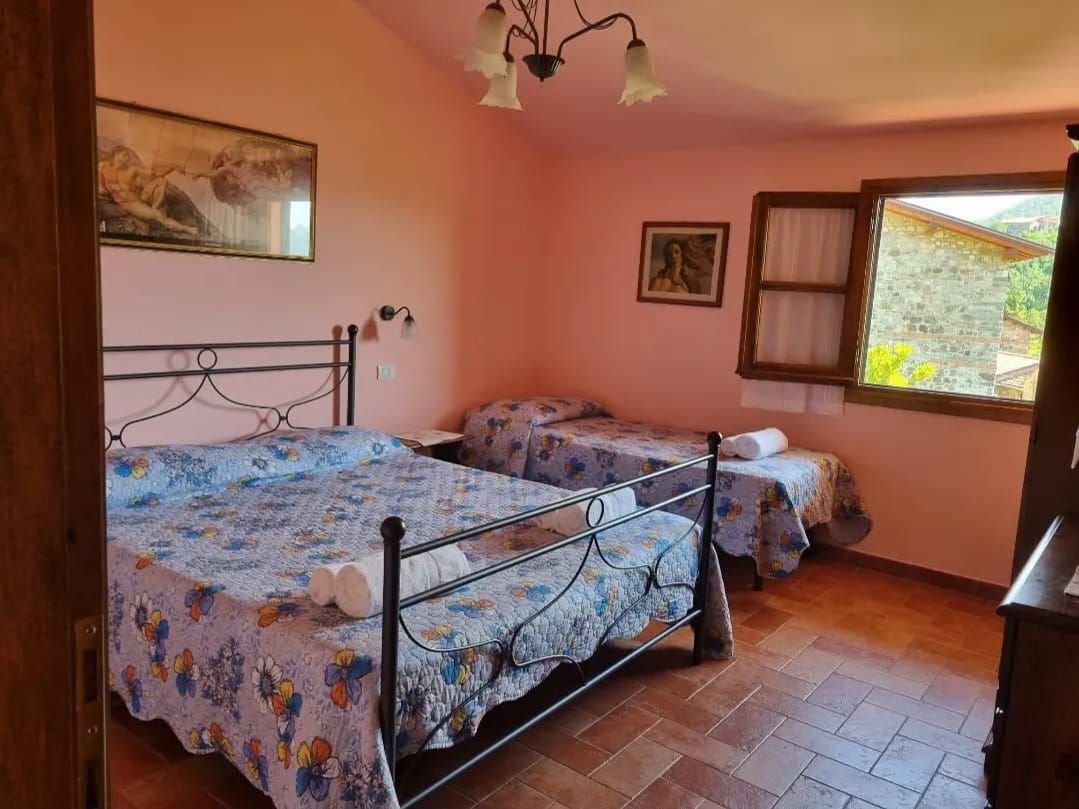 A bedroom with two beds, a window with curtains, and a painting on the wall.