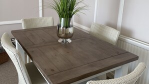 A dining table with a vase of flowers, surrounded by wicker chairs. - Stunning Sea Front Apartment (Hythe)