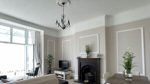 A spacious living room with a fireplace, a television, and a dining area with chairs. - Stunning Sea Front Apartment (Hythe)