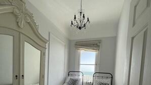 A bedroom with two single beds, a large mirror cabinet, and a chandelier. - Stunning Sea Front Apartment (Hythe)