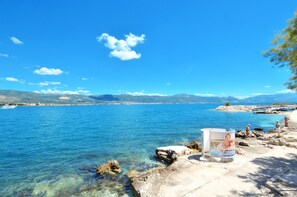A coastal view with clear blue water, rocky shore, and a distant mountain range. - C - apt w. Balcony, Shared Terrace & the sea View (Trogir)