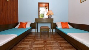 A room with two single beds, a small table with a lamp, and a mirror above the table.