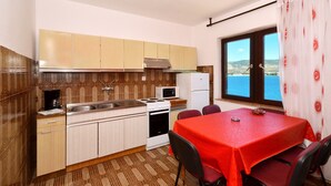 A compact kitchen with a dining area, featuring a stove, microwave, and refrigerator.