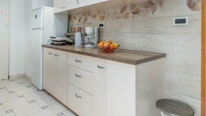 Una cocina moderna con armarios blancos, una encimera de madera y un frutero.
