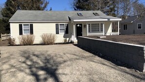Ein eingeschossiges Haus mit Veranda, Garage und einem kleinen Anbau.