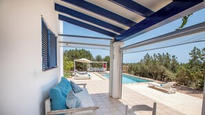 Un espace extérieur aménagé, abrité et doté d’une piscine et de chaises longues.