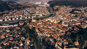 An aerial view of a town with a river running through it, surrounded by hills. - MOLDO HOUSE, "CASA MOLDO", AT THE FOOT OF THE MEDIEVAL FORTRESS, CENTRAL (Sighișoara)