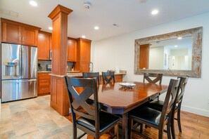 Une cuisine moderne avec des meubles en bois, un réfrigérateur en acier inoxydable et une table à manger avec des chaises.