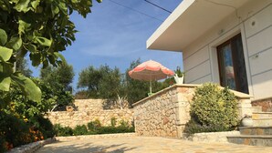 A stone-paved courtyard with a stone wall, a small bush, and a red and white umbrella. - Prefect place to spend your holidays ! (Ksamil)