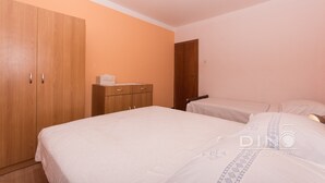 Une chambre à coucher avec une grande armoire, une table de chevet et un lit recouvert d’une couvre-lit à motifs.