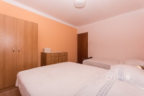 A bedroom with a large wardrobe, a bedside table, and a bed with a patterned bedspread.