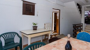 Un coin repas avec une table dressée pour deux personnes, une plante en pot et une chaise.