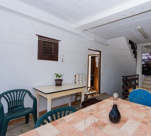 A dining area with a table set for two, a potted plant, and a chair.